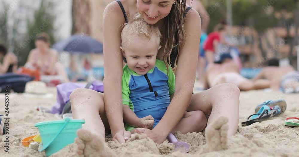Mom and her son are building sand castles on the beach. Mom and her son are building sand castles on the beach.