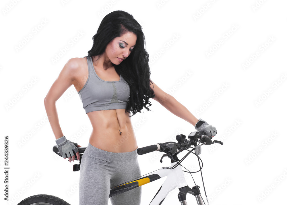 Woman on a bicycle dressed in a sports uniform in gray in the studio on a white background