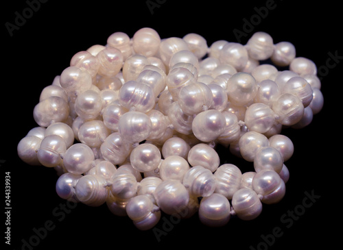 Thread of natural white baroque pearl beads on black background