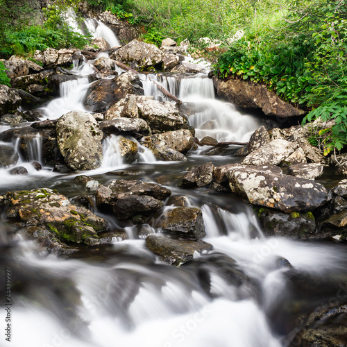 Waterfall in mountains. Rapid flow in river. Water in rocks  trip along river.