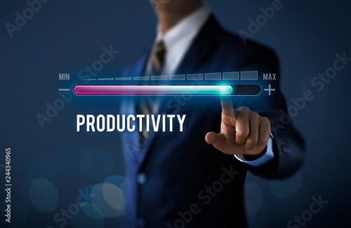 Increase productivity concept. Businessman is pulling up progress bar with the word PRODUCTIVITY on dark tone background. photo