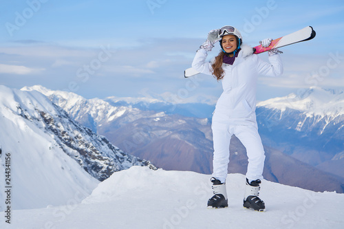 Portrait of beautiful woman with ski and ski suit in winter mountain.