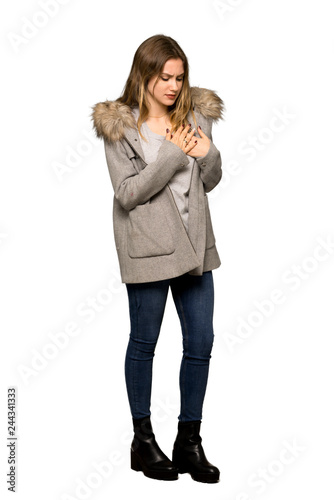 A full-length shot of a Teenager girl with coat having a pain in the heart on isolated white background © luismolinero