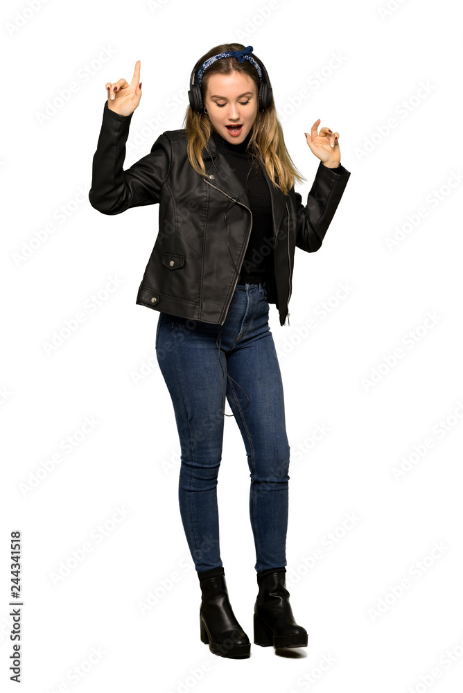 A full-length shot of a Teenager girl with leather jacket listening to music with headphones and dancing on isolated white background A full-length shot of a Teenager girl with leather jacket listening to music with headphones and dancing on isolated white background