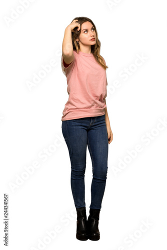 A full-length shot of a Teenager girl with pink sweater having doubts while looking up on isolated white background