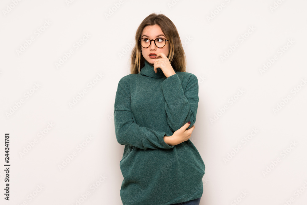 Teenager girl over white wall having doubts while looking up Teenager girl over white wall having doubts while looking up