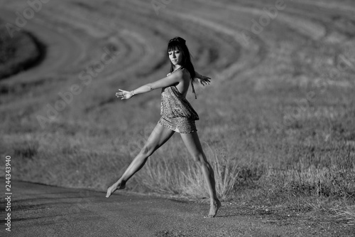 Beautiful woman dancing and going across a countrysde road.