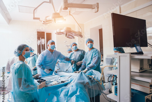 Process of gynecological surgery operation using laparoscopic equipment. Group of surgeons in operating room with surgery equipment photo