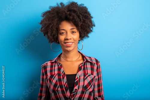 Portrait of cool young black woman laughing against blue wall - Imagem © paulovilela