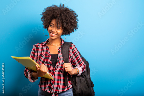 young african student with backpack on the back on blue background