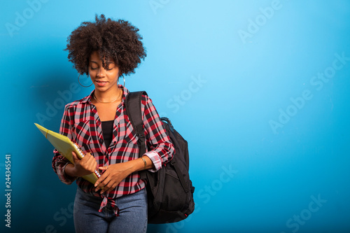 young african student with backpack on the back on blue background