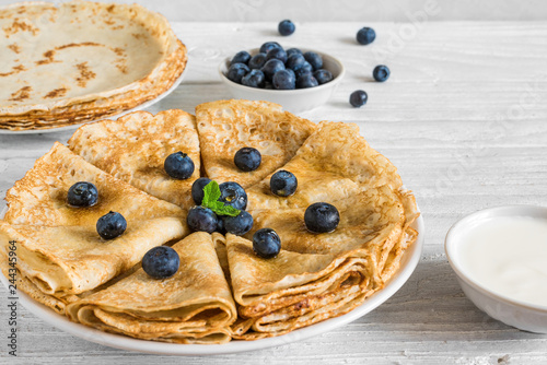 Homemade crepes or thin pancakes served with fresh blueberries, sour cream and mint photo