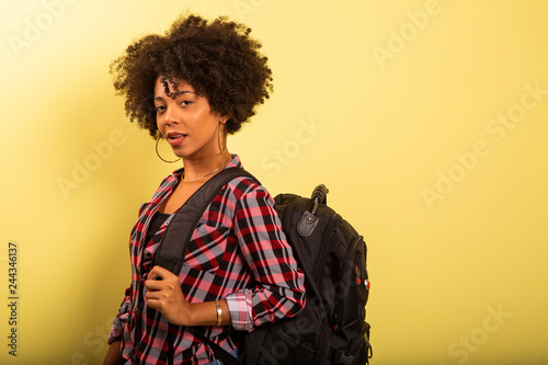 young african student with backpack on the back on yellow background