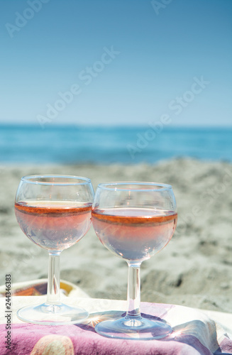 Beach party with sea view, romantic celebration on sunny sandy beach, two glasses with rose wine