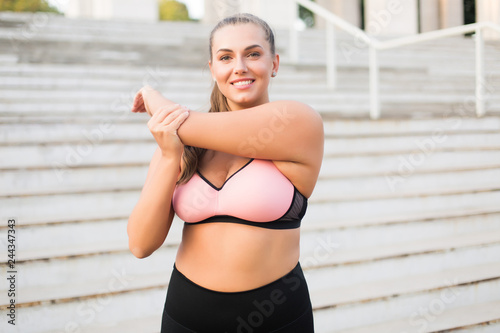 Portrait of smiling young woman stretching outdoors photo