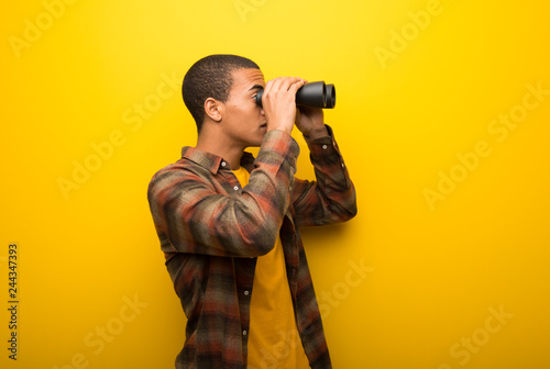 фотографія Young african american man on vibrant yellow background and looking for somethin