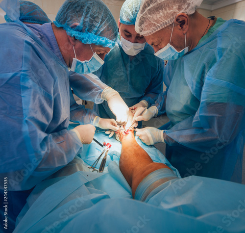 Process of trauma surgery operation. Group of surgeons in operating room with surgery equipment.