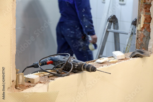 Closeup professional construction dusty drill, puncher on background of workman, building tools. Concept installation and dismantling windows and doors in office building