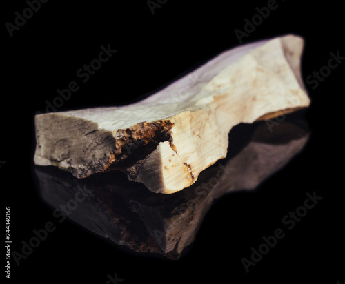 Piece of natural petrified wood with opal on black background with reflection