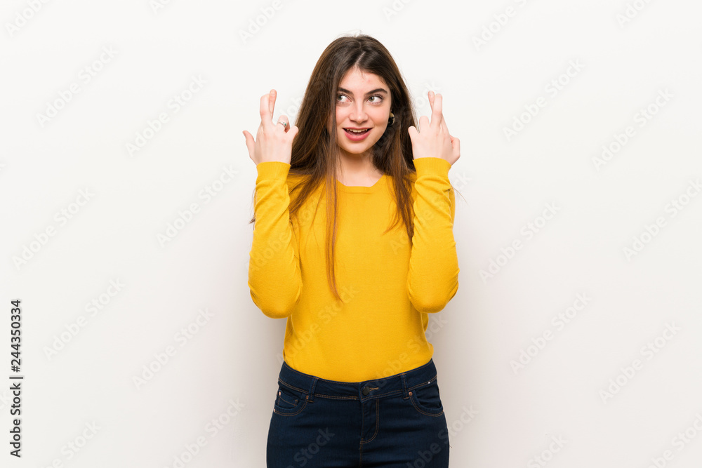 Young woman with yellow sweater with fingers crossing and wishing the best Young woman with yellow sweater with fingers crossing and wishing the best