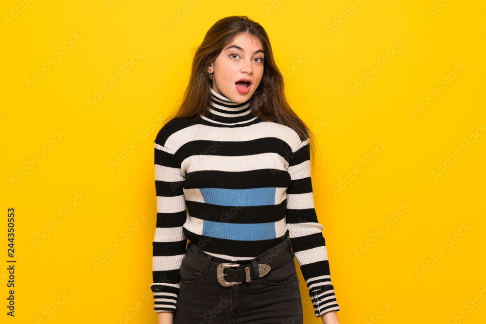 Young woman over yellow wall with surprise and shocked facial expression Young woman over yellow wall with surprise and shocked facial expression