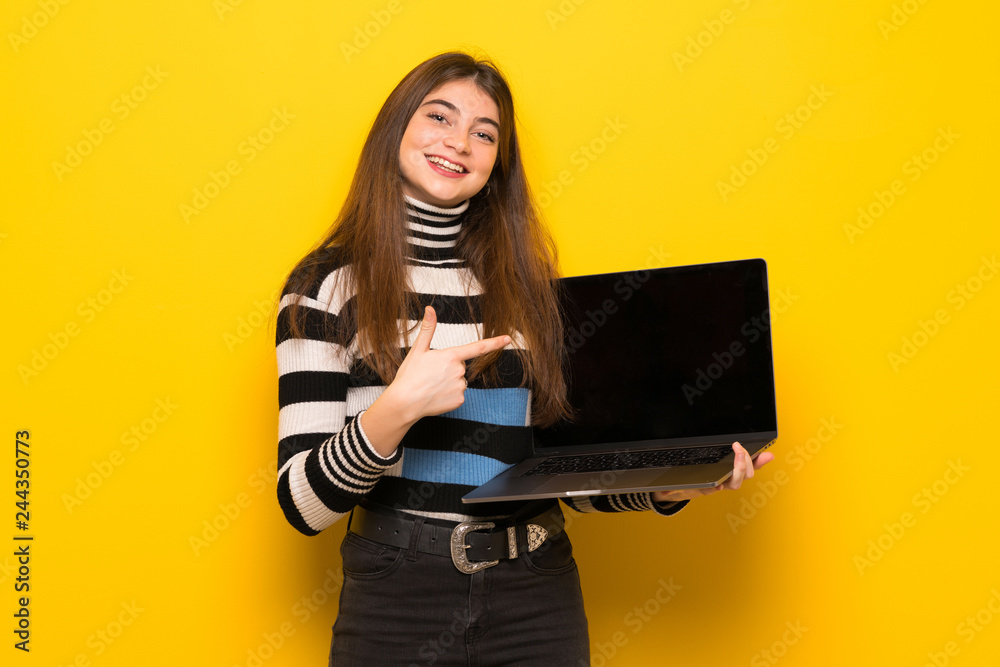 Young woman over yellow wall showing a laptop Young woman over yellow wall showing a laptop