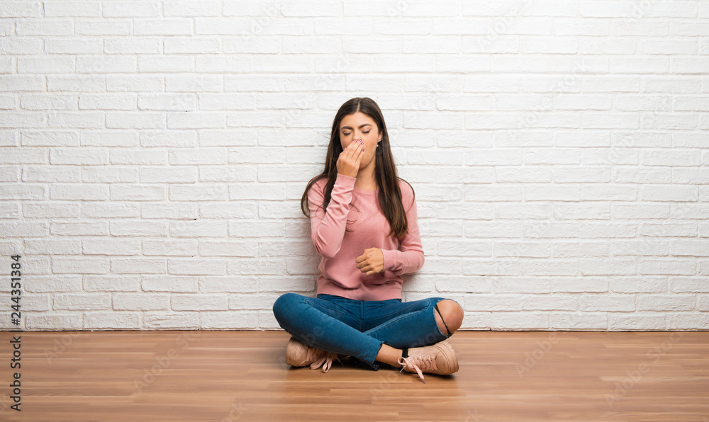 Teenager girl sitting on the floor in a room is suffering with cough and feeling bad