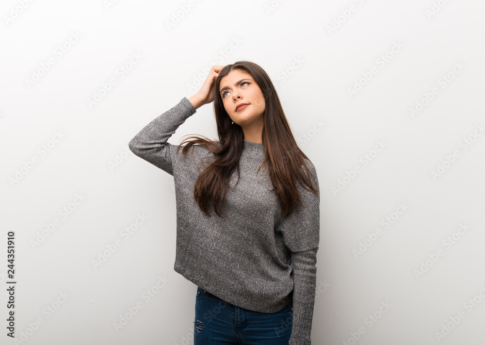Teenager girl on isolated white backgorund having doubts while scratching head Teenager girl on isolated white backgorund having doubts while scratching head