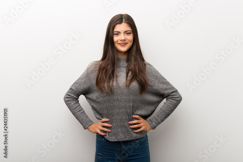 Teenager girl on isolated white backgorund posing with arms at hip and laughing looking to the front