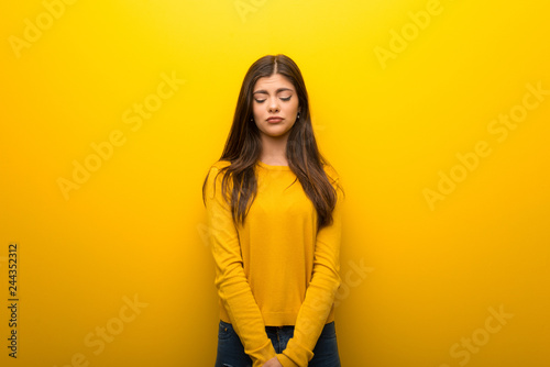 Teenager girl on vibrant yellow background with sad and depressed expression