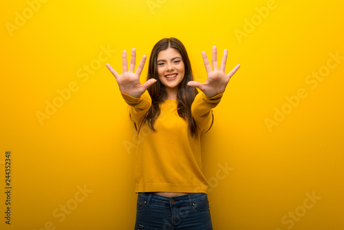 Teenager girl on vibrant yellow background counting ten with fingers photo