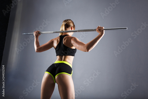 Butts and the back of a beautiful young woman fitness instructor posing against a gray background. Concept of sports lifestyle