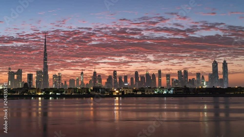 Sunrise in Dubai, dawn over Burj Khalifa. New day in Dubai under sun, beautiful colored cloudy sky over downtown from night to morning. Solar path on sea comes from Burj Khalifa