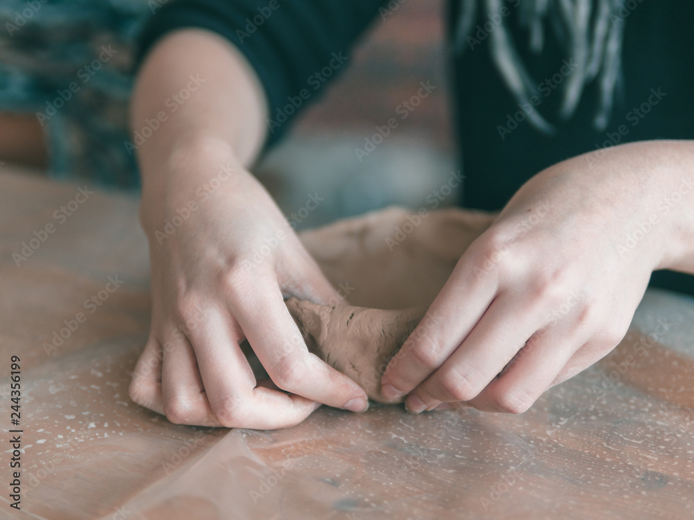 Female ceramist hands make trendy plate of brown clay. Close up view of fingers made fashion dessert flat plate on craft workshop. Female ceramist hands make trendy plate of brown clay. Close up view of fingers made fashion dessert flat plate on craft workshop.