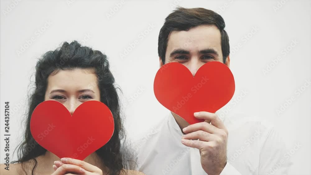 Beautiful romantic couple isolated on white background. An attractive young woman and handsome man hold red hearts in their hands. Valentine's Day Beautiful romantic couple isolated on white background. An attractive young woman and handsome man hold red hearts in their hands. Valentine's Day