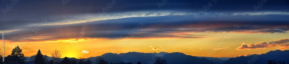 Tranquil panoramia scene of red sun and orange sky sunset over the Rocky Mountains in Colorado by Denver, United States.