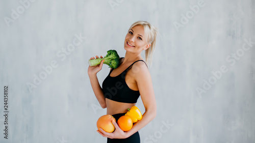sports woman holding fresh fruits and vegetables in hands, healthy eating concept