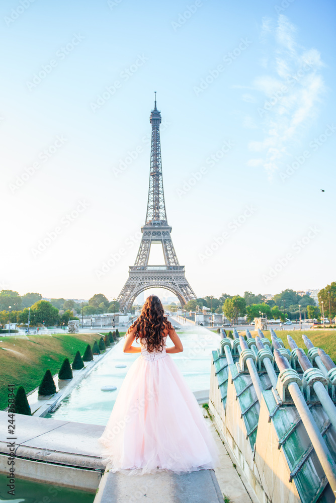 young woman in pink chiffon dress standing in front of the Eiffel tower in Paris