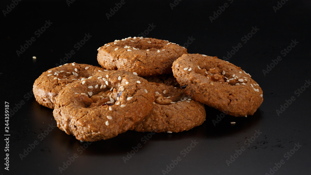 A bunch of homemade oatmeal cookies with nuts, chocolate chips and sesame. On a black background. A bunch of homemade oatmeal cookies with nuts, chocolate chips and sesame. On a black background.