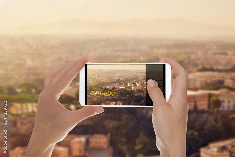 A man is making a photo of panorama of Rome on a mobile phone