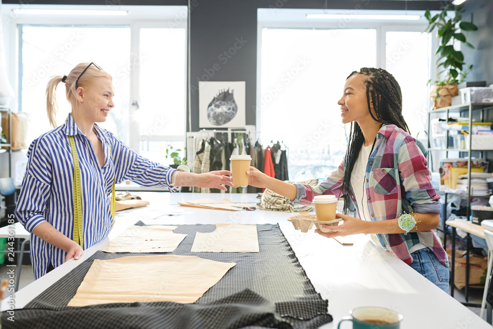 Female fashion designers have a coffee break while sewing new dress in atelier Female fashion designers have a coffee break while sewing new dress in atelier