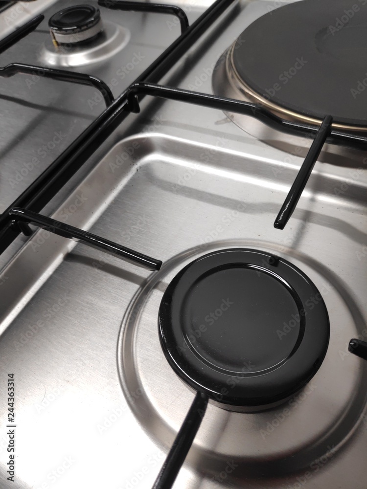 Gas burners on stainless steel gas fired freestanding hob. In the image can be seen the burner caps together with the burner body and cast iron pan support