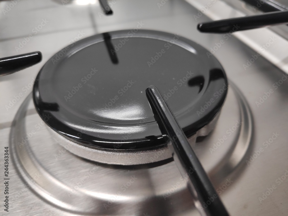 Gas burners on stainless steel gas fired freestanding hob. In the image can be seen the burner caps together with the burner body and cast iron pan support Gas burners on stainless steel gas fired freestanding hob. In the image can be seen the burner caps together with the burner body and cast iron pan support