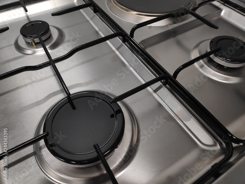 Gas burners on stainless steel gas fired freestanding hob. In the image can be seen the burner caps together with the burner body and cast iron pan support