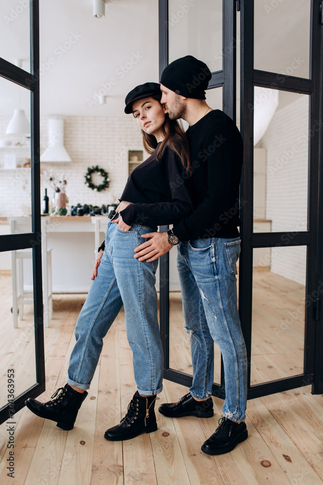 Two hipster models: a man and a woman in a blank black t-shirt, jeans and posing. in a black hat, cap, love, kisses Two hipster models: a man and a woman in a blank black t-shirt, jeans and posing. in a black hat, cap, love, kisses