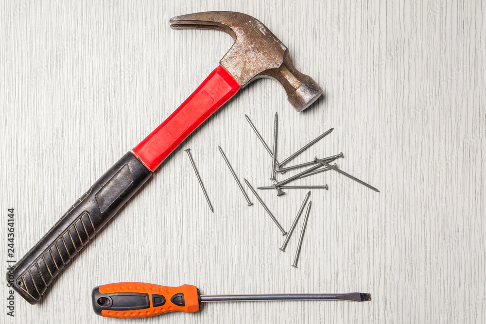 An image of hammer, screwdriver and nails on wooden table An image of hammer, screwdriver and nails on wooden table