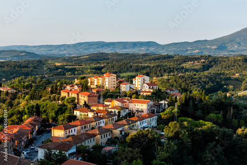 Chiusi village cityscape at sunrise in Umbria Italy street road cars and rooftop houses on mountain countryside and rolling hills photo