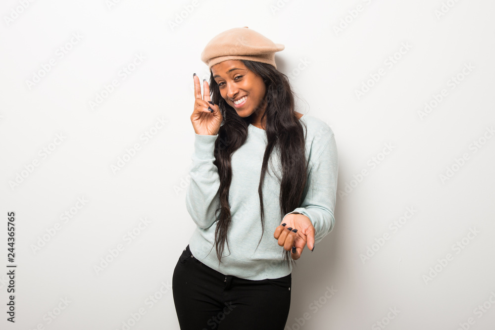 Young afro american woman on white wall happy and counting two with fingers