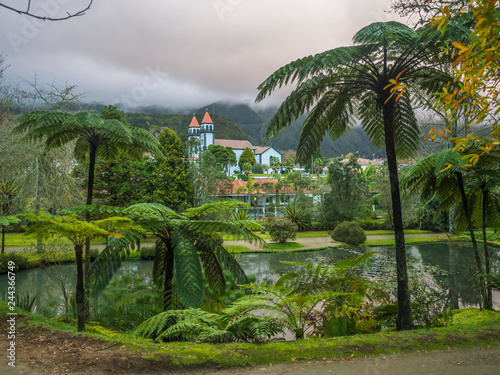 Church in Furnas village viewed from the Terra Nostra garden Botanical Park with thermal lakes and pool and tree ferns in Sao Miguel Azores islands. Portugal photo