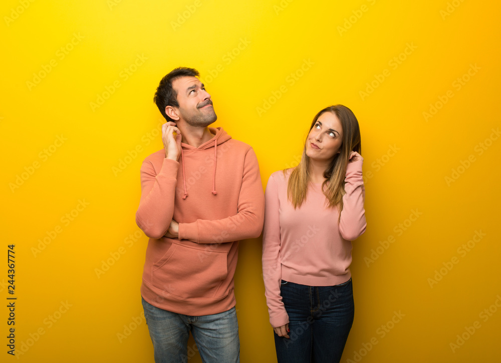 Group of two people on yellow background thinking an idea while scratching head Group of two people on yellow background thinking an idea while scratching head